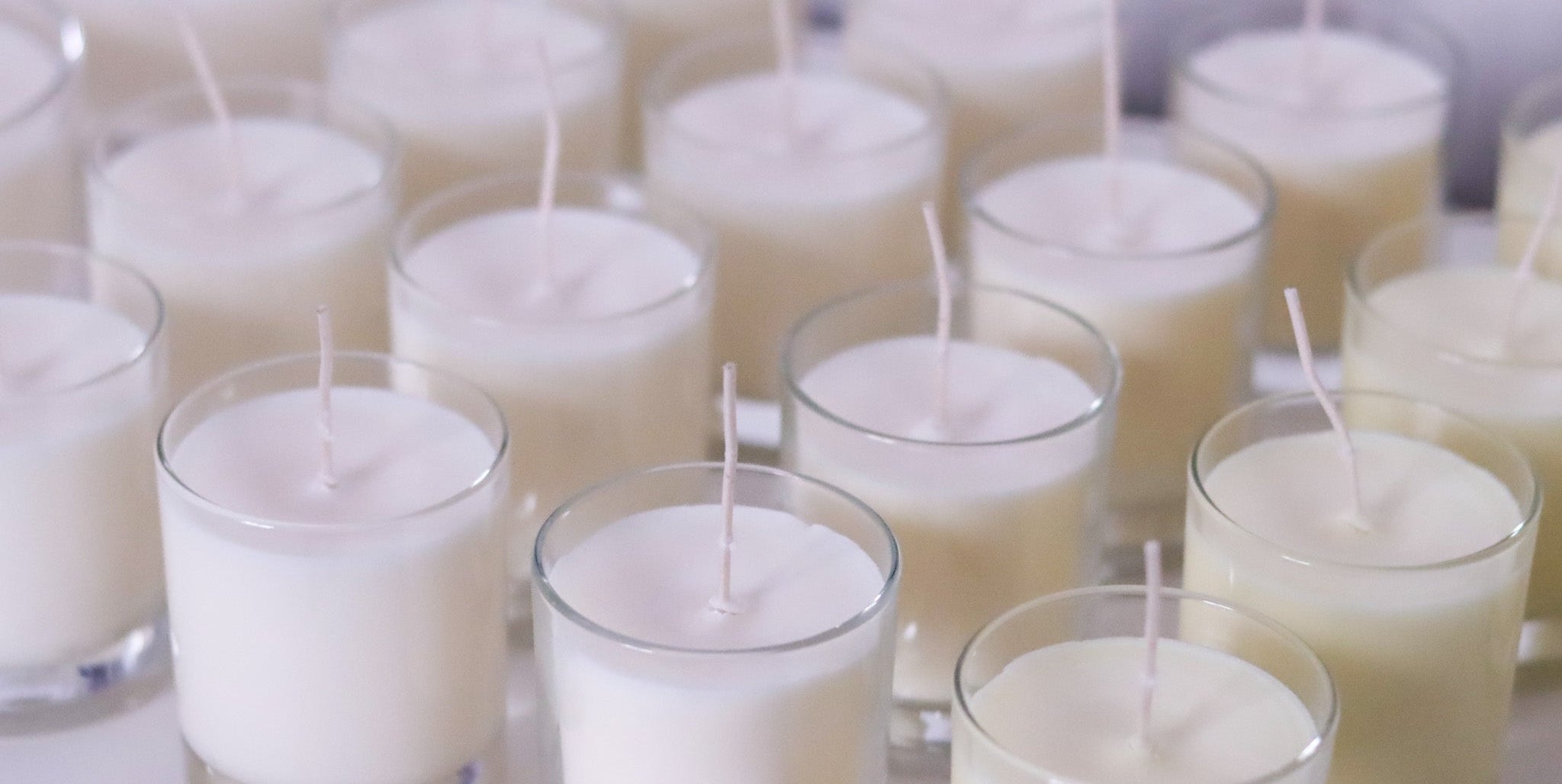 Multiple small candles in glass holders on a white surface